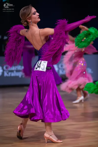 Dancesport competitor: Female dancer: purple satin and sequin dress with large purple feather sleeves a