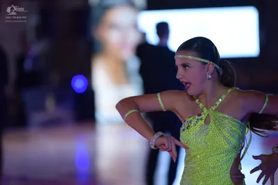Dancesport competitor: Female dancer in foreground: bright lime green sequined Latin dress with thin cr
