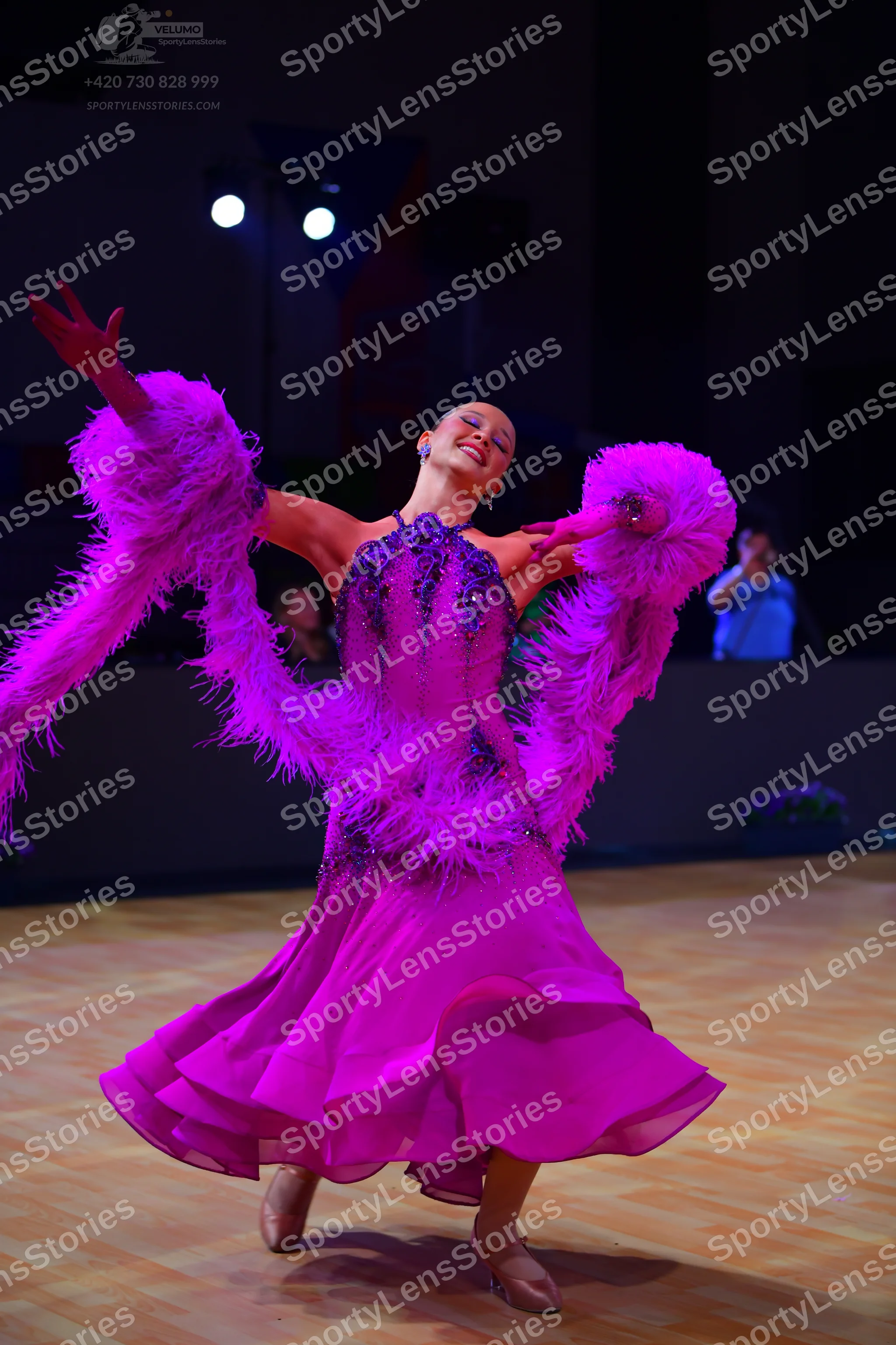 Dancesport competitor: Female dancer: magenta/pink ballroom dress with a dark sequined bodice, large pi