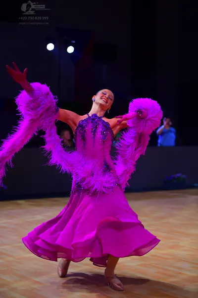Dancesport competitor: Female dancer: magenta/pink ballroom dress with a dark sequined bodice, large pi
