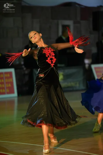 Dancesport competitor: Female dancer: black ballroom dress with red floral sequin patterns on the bodic