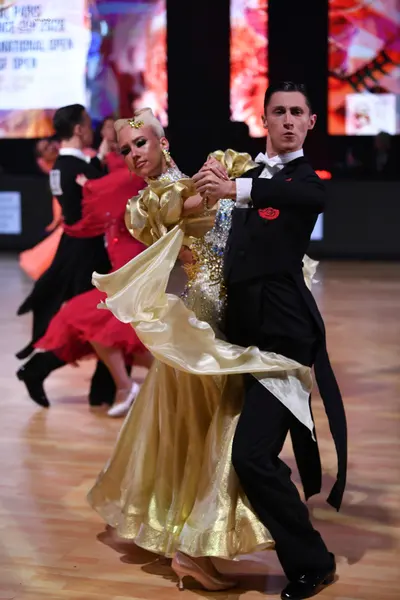 Dancesport competitor: Male dancer: black tailcoat with a white shirt, white bow tie, and a red floral 