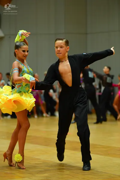Dancesport competitor: Female dancer: yellow and light blue latin dress with a ruffled yellow skirt and