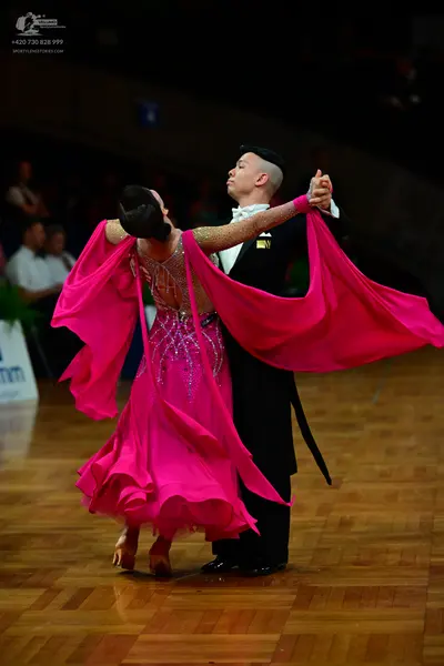 Dancesport competitor: Female dancer: bright pink latin dress with a sheer, embellished bodice and long