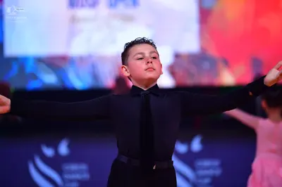 Dancesport competitor: Male dancer: black long-sleeved shirt, black trousers, and a black necktie