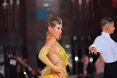 Dancesport competitor: Female dancer: bright yellow Latin dance dress with sequins, cutouts, and fringe