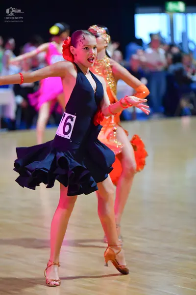 Dancesport competitor #76: Female dancer: black halter neck latin dress with a ruffled skirt, red hair acce