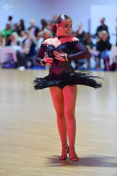 Dancesport competitor: Female dancer: black Latin dance costume featuring a long-sleeved, semi-sheer bl
