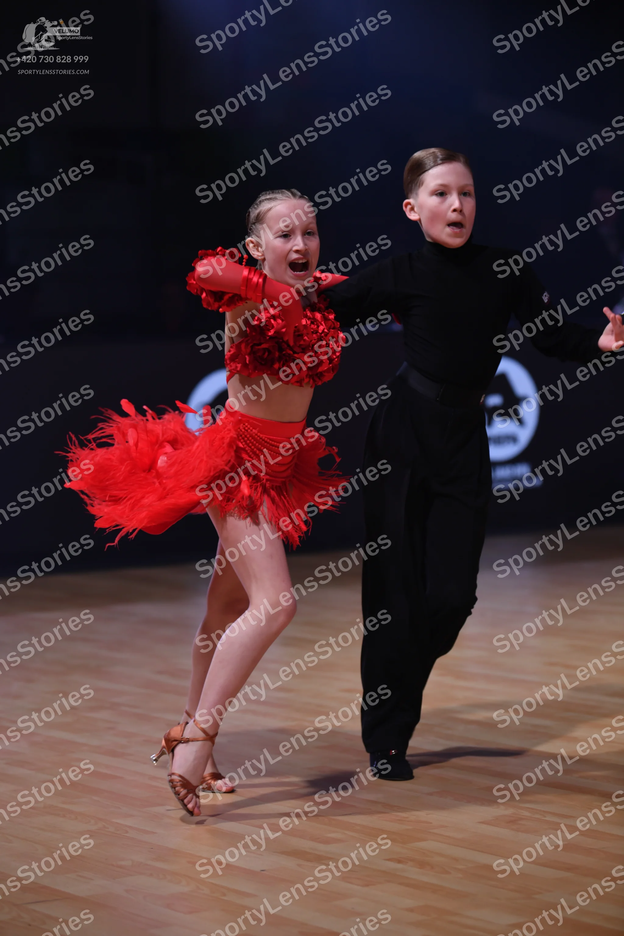 Dancesport competitor: Female dancer: red Latin dance costume featuring a textured/embellished top, lon