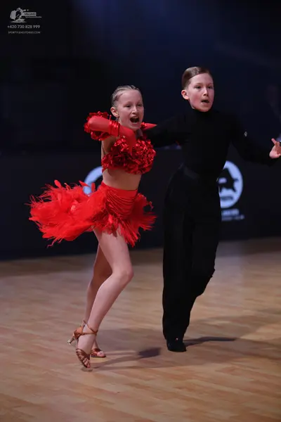 Dancesport competitor: Female dancer: red Latin dance costume featuring a textured/embellished top, lon