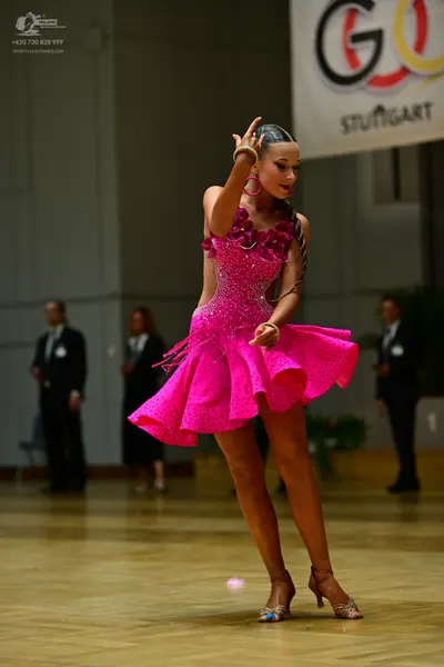 Dancesport competitor: Female dancer: bright pink Latin dance dress with rhinestone embellishments and 