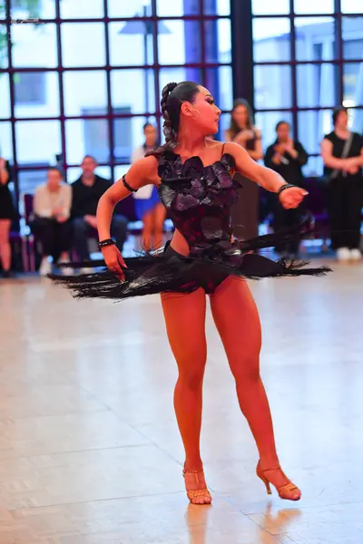 Dancesport competitor: Female dancer: black Latin dance dress with a sequined or textured bodice and a 