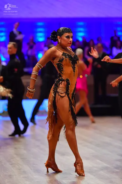 Dancesport competitor: Main female dancer: tan Latin dance dress with a black sequined/beaded bodice an