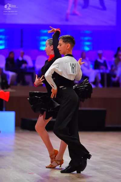 Dancesport competitor: Male dancer: white and black long-sleeved shirt, black trousers, and black dance