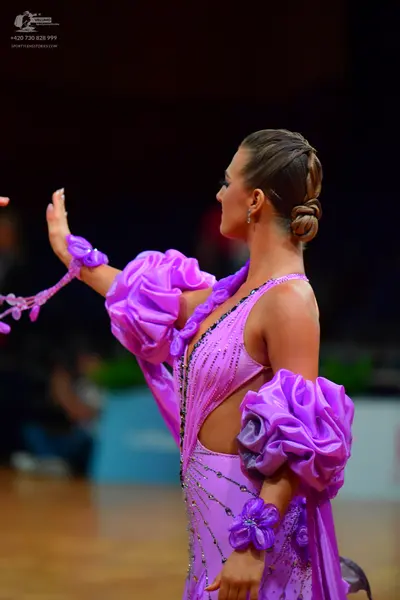 Dancesport competitor: Female dancer: purple latin dress with large ruffled satin-like sleeves, sparkly