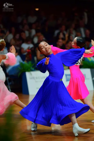 Dancesport competitor: Dancer on the left: light pink, ruffled/voluminous dress
