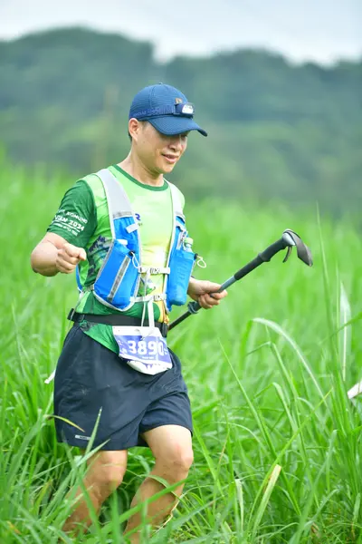 Marathon runner #3688: Runner 1: green jersey, black shorts, blue and white hydration vest, blue cap