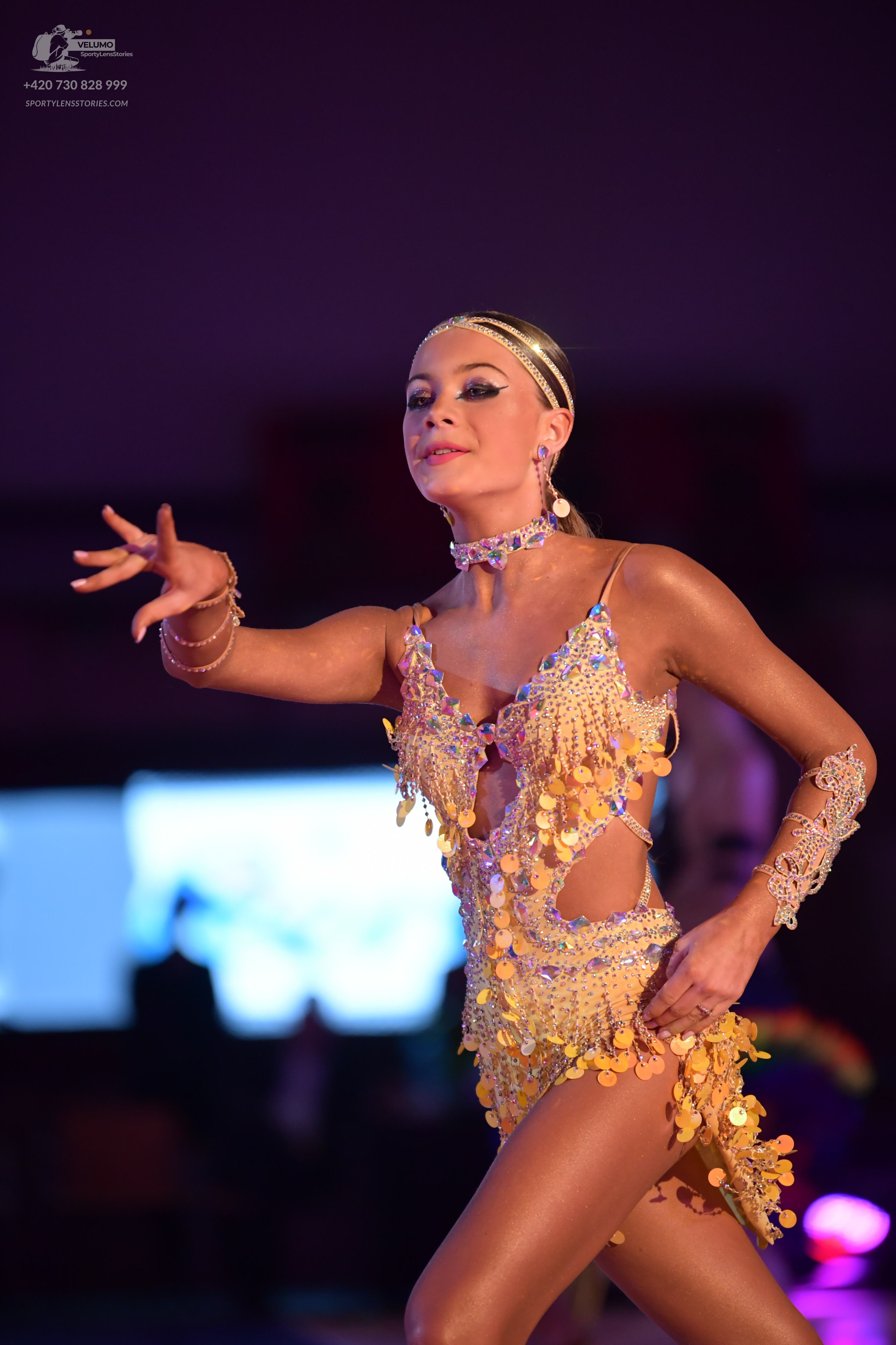 Dancesport competitor: Female dancer: gold latin dress with sequins and large metallic coin-like fringe