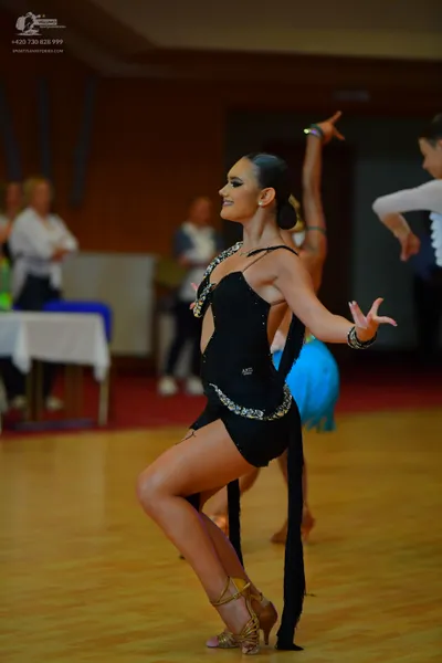 Dancesport competitor: Female dancer in foreground: black Latin dress with rhinestone embellishments al
