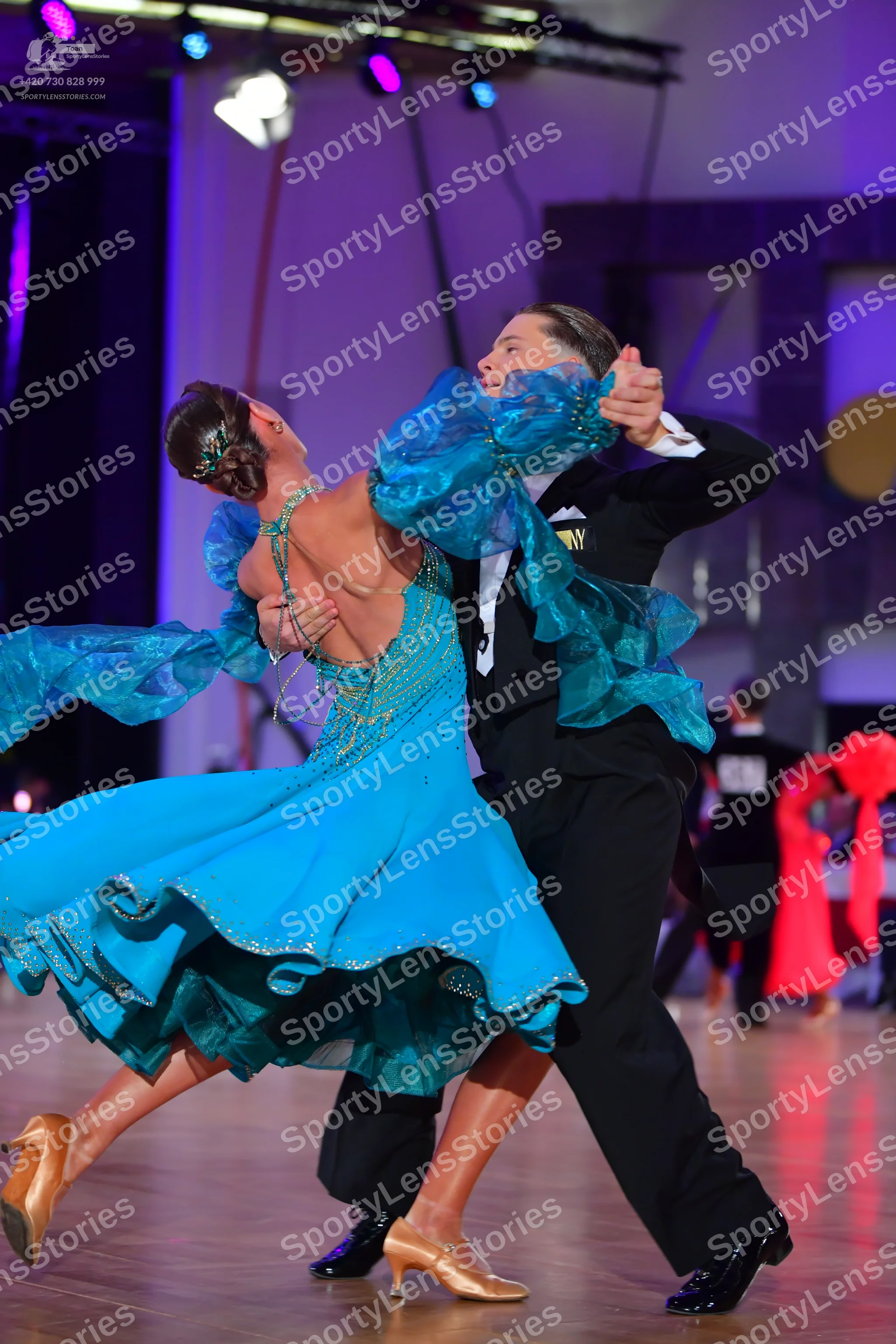 Dancesport competitor: Female dancer: teal ballroom dress with voluminous, sheer, ruffled sleeves and s