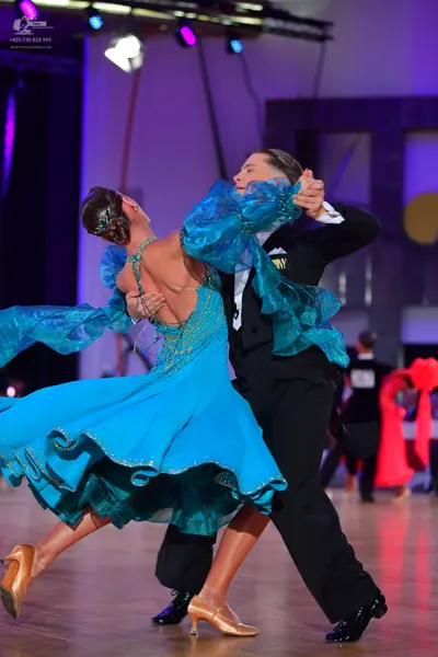 Dancesport competitor: Female dancer: teal ballroom dress with voluminous, sheer, ruffled sleeves and s