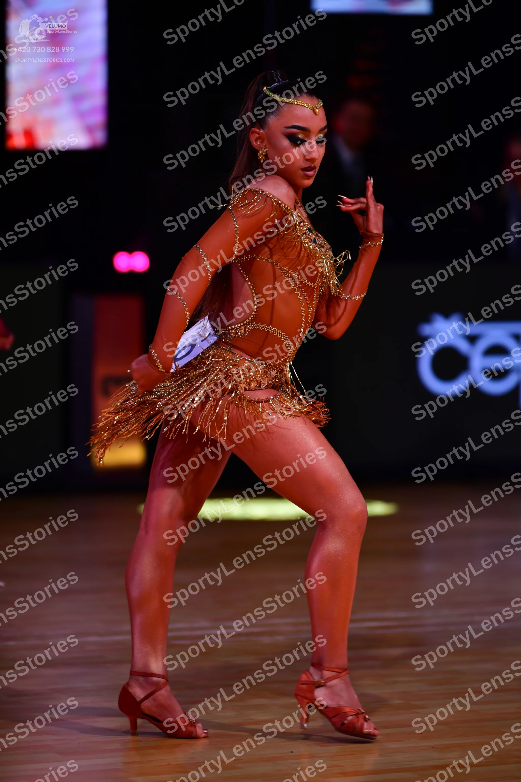 Dancesport competitor: Female dancer: gold latin dance dress with sheer mesh, sequins, and long fringe