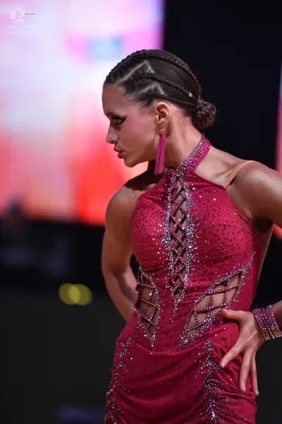 Dancesport competitor: Female dancer: magenta latin dress with sequins, featuring a high neck with lace