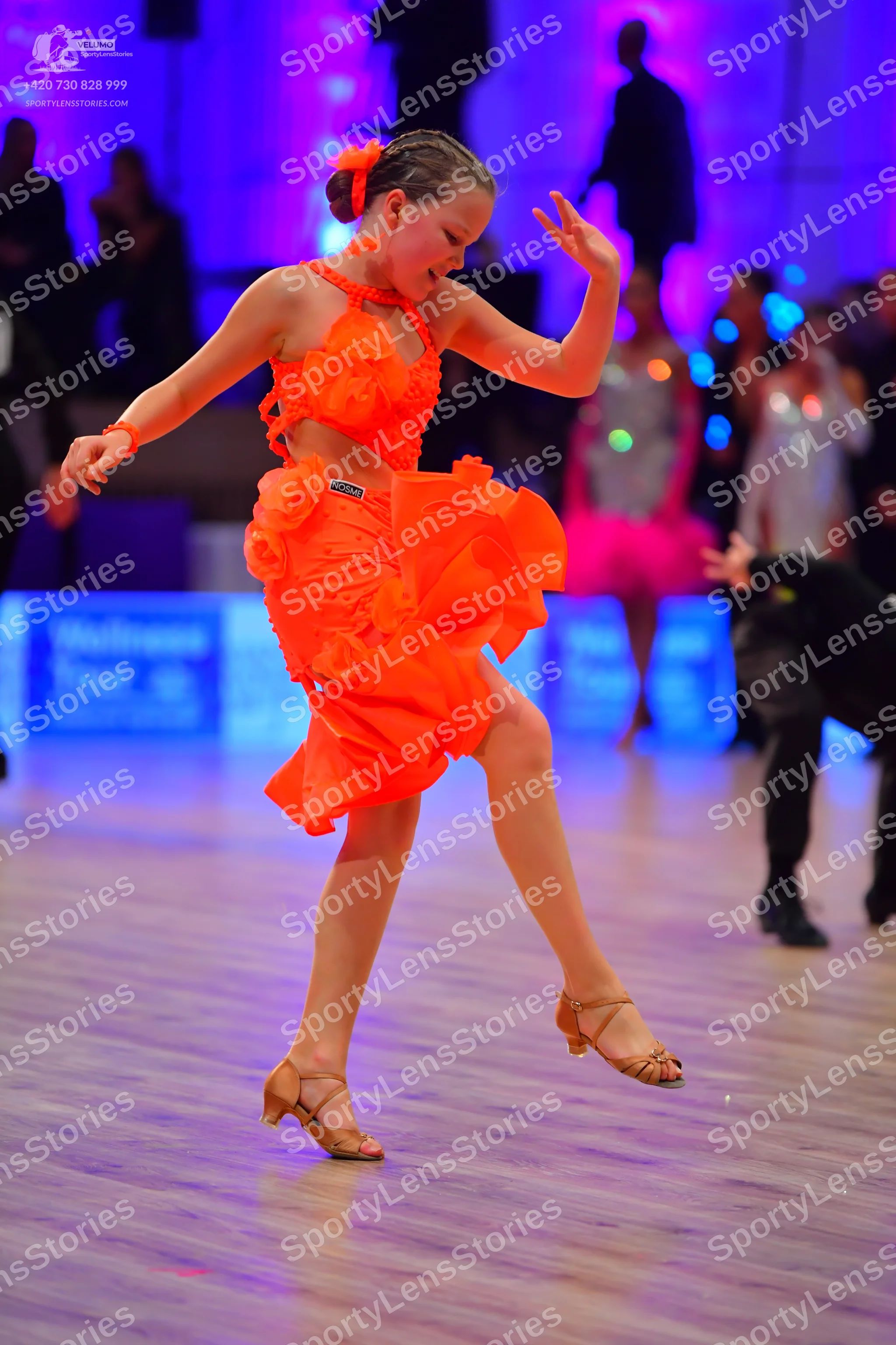 Dancesport competitor: Main female dancer: bright orange Latin dress with a ruffled, layered skirt and