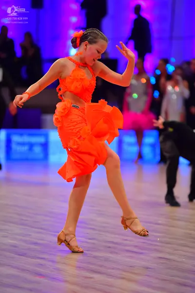 Dancesport competitor: Main female dancer: bright orange Latin dress with a ruffled, layered skirt and 