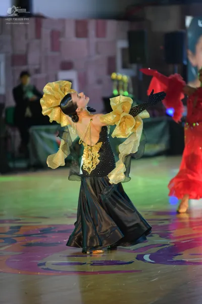 Dancesport competitor: Female dancer in center: black and gold ballroom dress with a sequined black bod