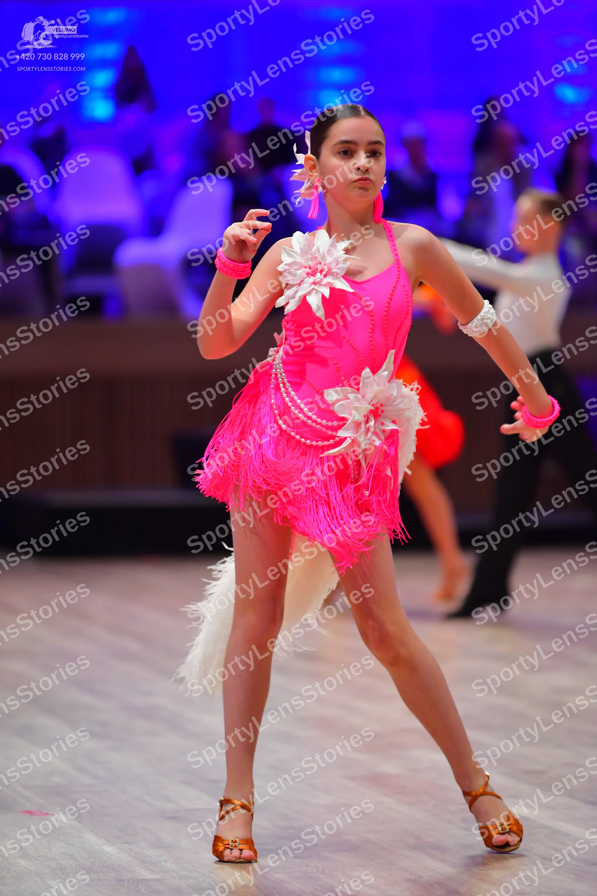 Dancesport competitor: Female dancer: bright pink Latin dance dress with fringe, large white 3D flower