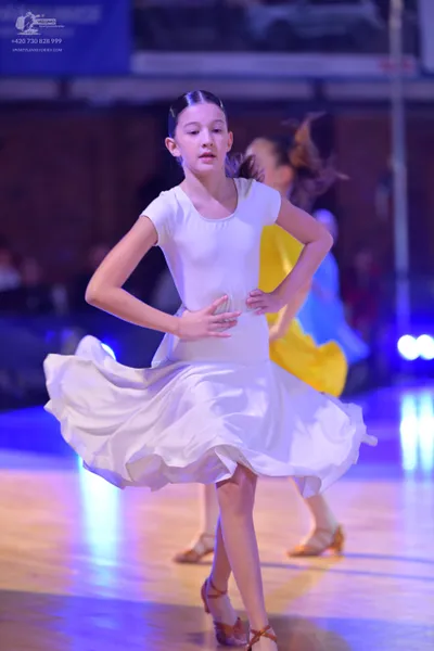 Dancesport competitor: Female dancer in foreground: white short-sleeved dress with a flared skirt