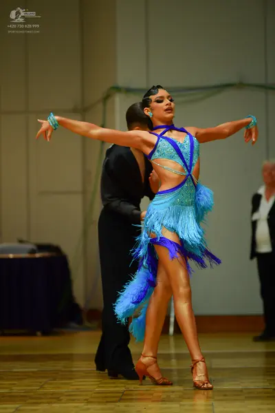 Dancesport competitor: Female dancer: light blue latin dance dress with dark blue trim, sequins, and lo