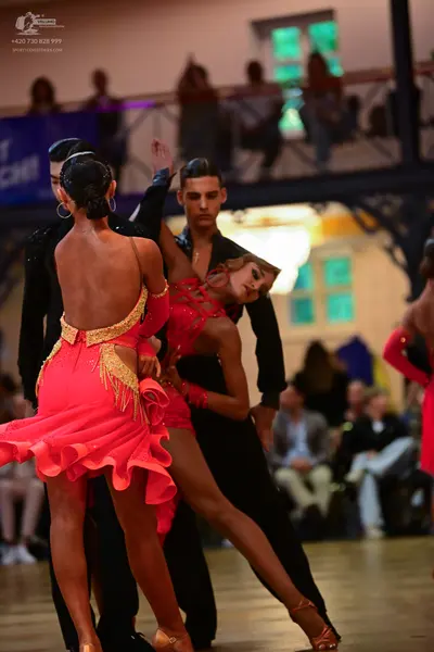 Dancesport competitor: Female dancer 1: bright pink Latin dress with a ruffled skirt and sheer mesh sle