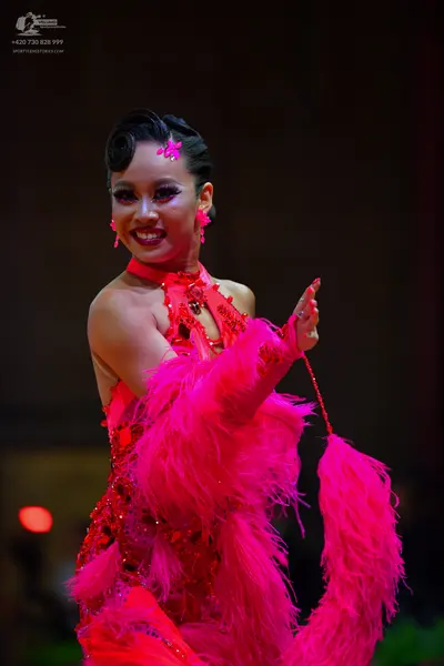 Dancesport competitor: Female dancer: bright pink latin dress with sequins and large pink feathers on t