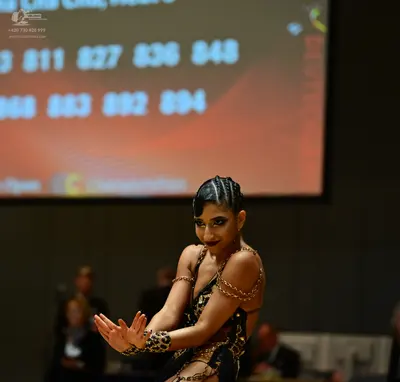 Dancesport competitor: Female dancer: black Latin dance costume with gold and bronze sequin patterns, t