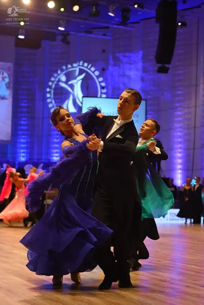 Dancesport competitor: Primary female dancer: blue ballroom gown with a sparkly, sequined bodice and da