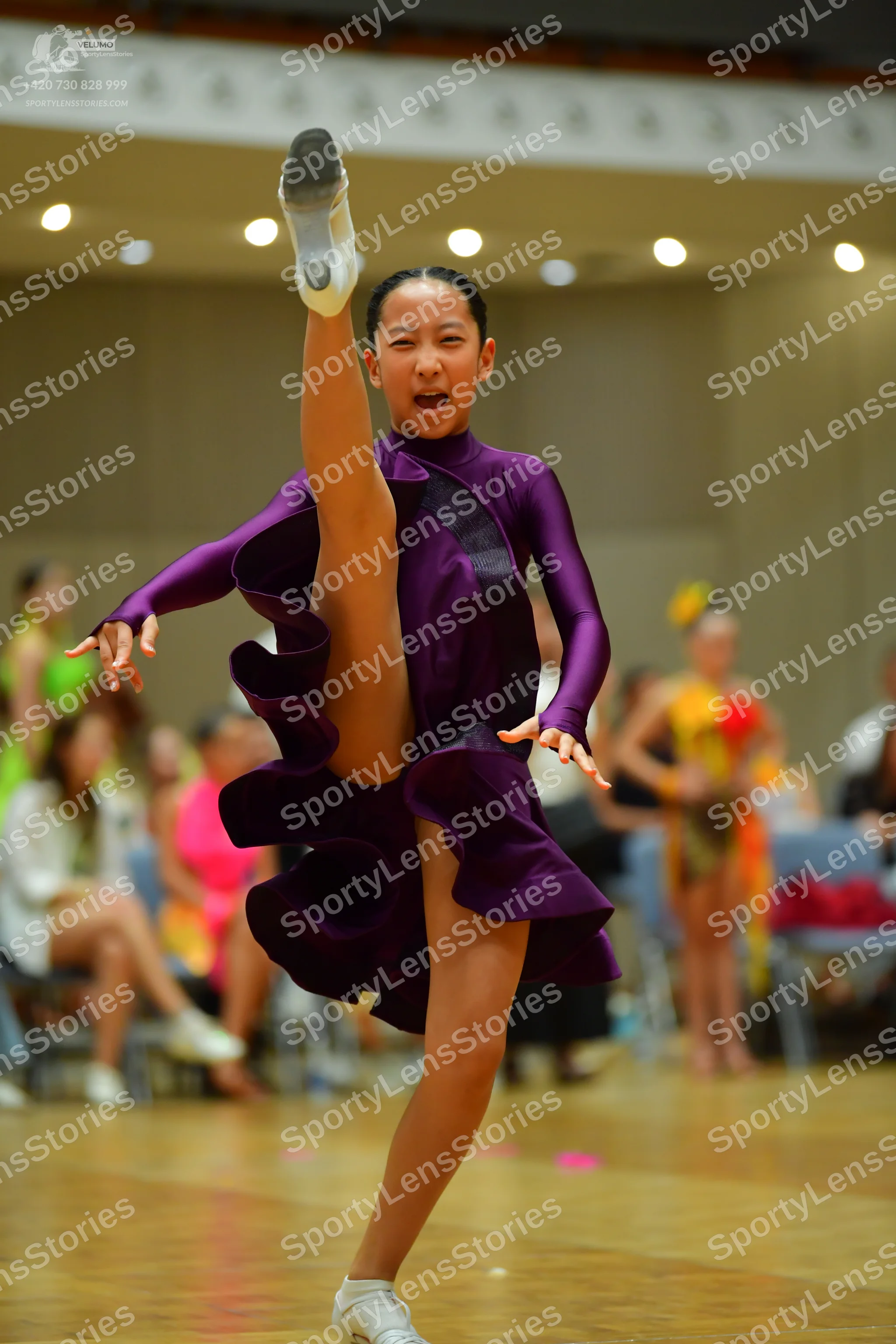Dancesport competitor: Primary dancer: purple long-sleeved dress with a high neckline and large, volumi