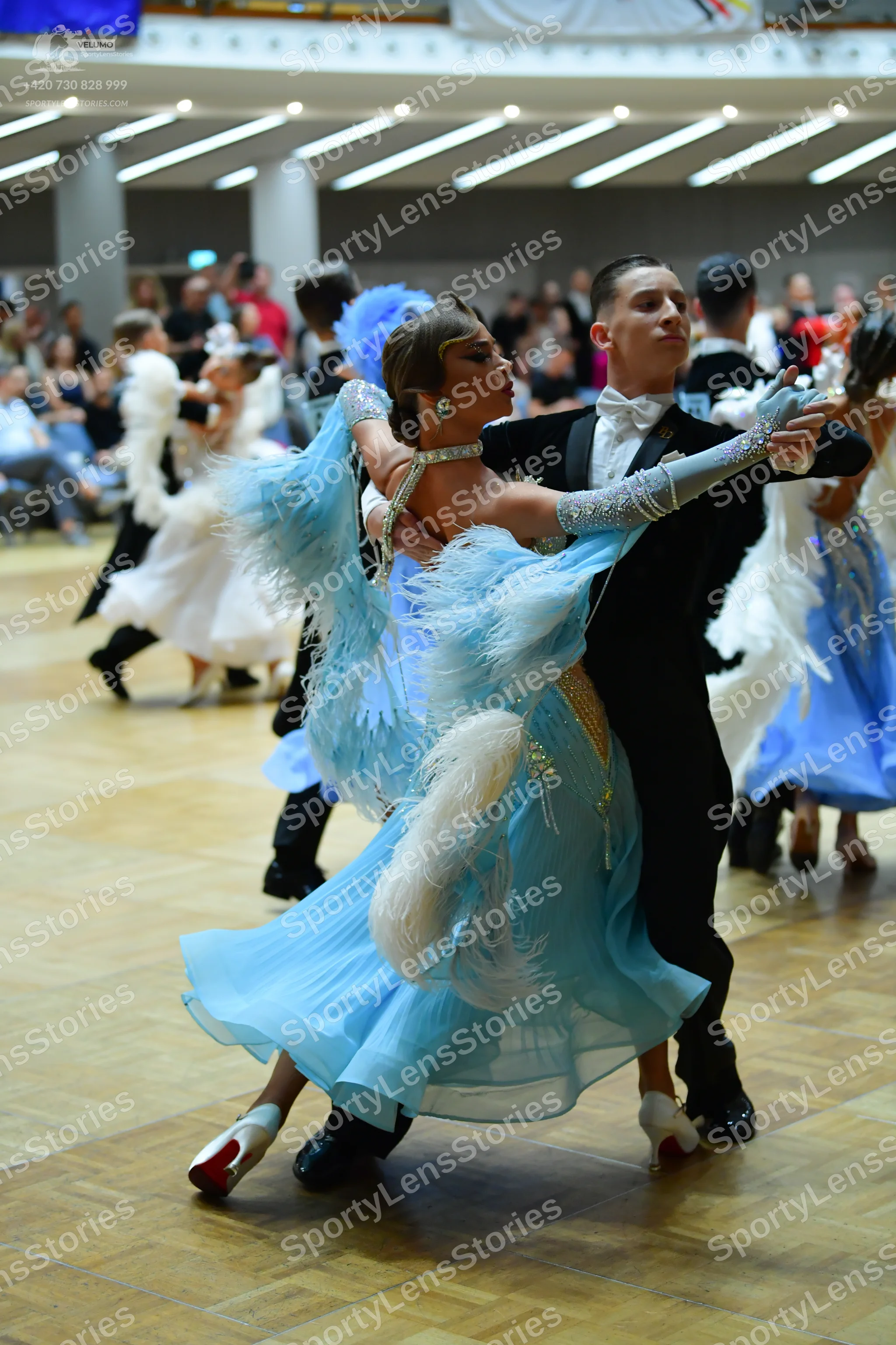 Dancesport competitor: Main female dancer: light blue ballgown with voluminous feathery sleeves and ski