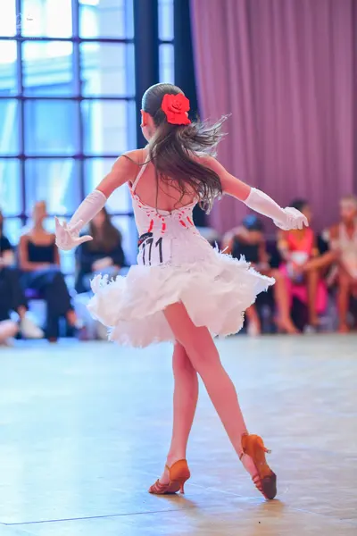 Dancesport competitor #771: Female dancer: white ruffled Latin dance dress with red accents, long white glov