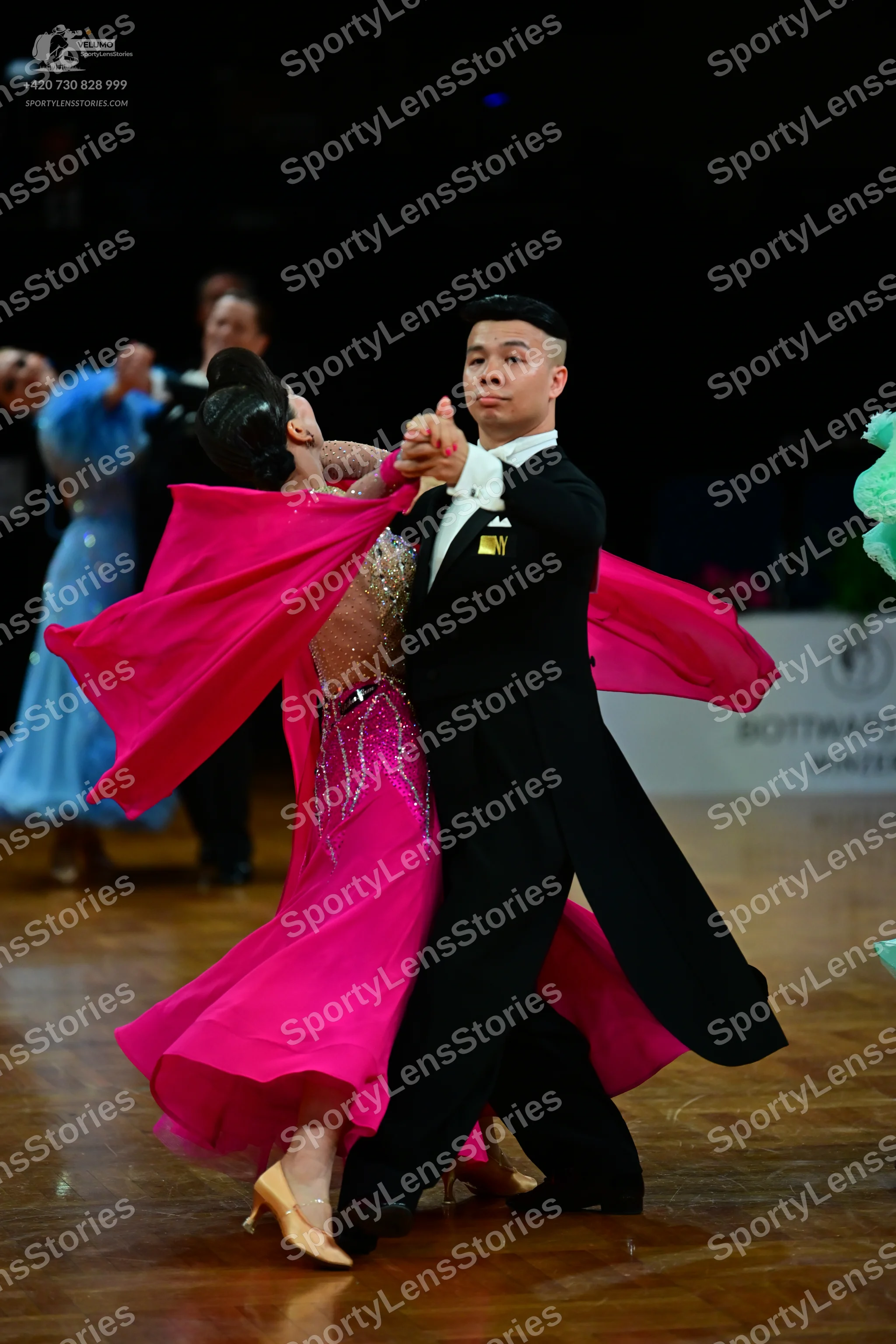 Dancesport competitor: Female dancer in foreground: bright pink ballgown with silver sequin detailing o