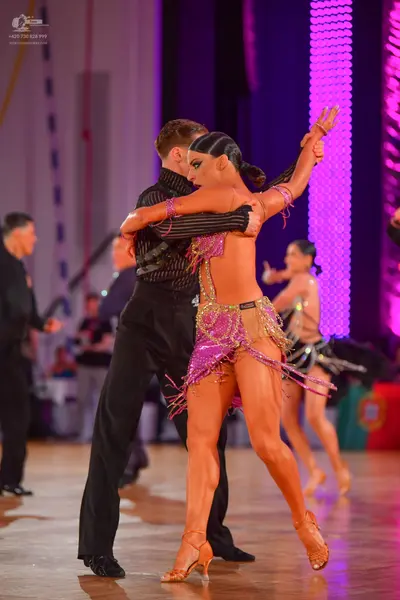 Dancesport competitor: Male dancer in foreground: black textured long-sleeve shirt and black trousers