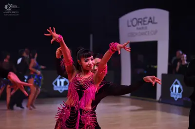 Dancesport competitor: Foreground female dancer: bright pink/magenta Latin dance dress with extensive f
