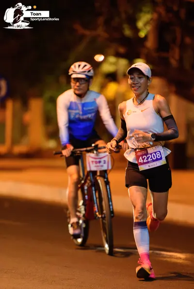 Marathon runner #42208: Runner 1: white tank top, black shorts, pink shoes, white cap, grey arm sleeve, 