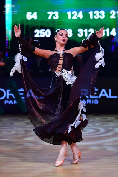 Dancesport competitor: Female dancer: black latin dress with white feather accents and cut-outs on the 