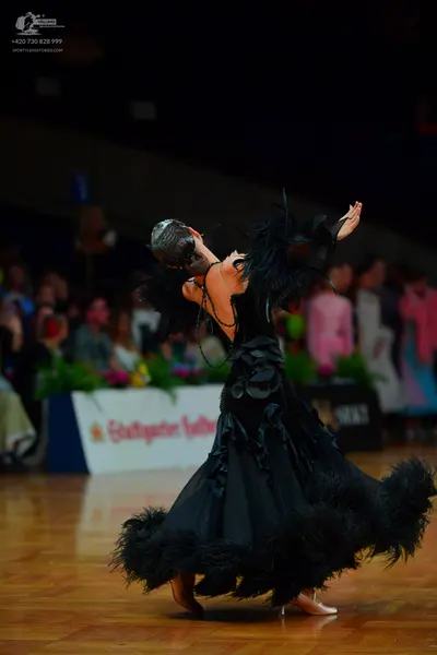 Dancesport competitor: Female dancer: black ballgown with voluminous black feathers on the skirt and sl