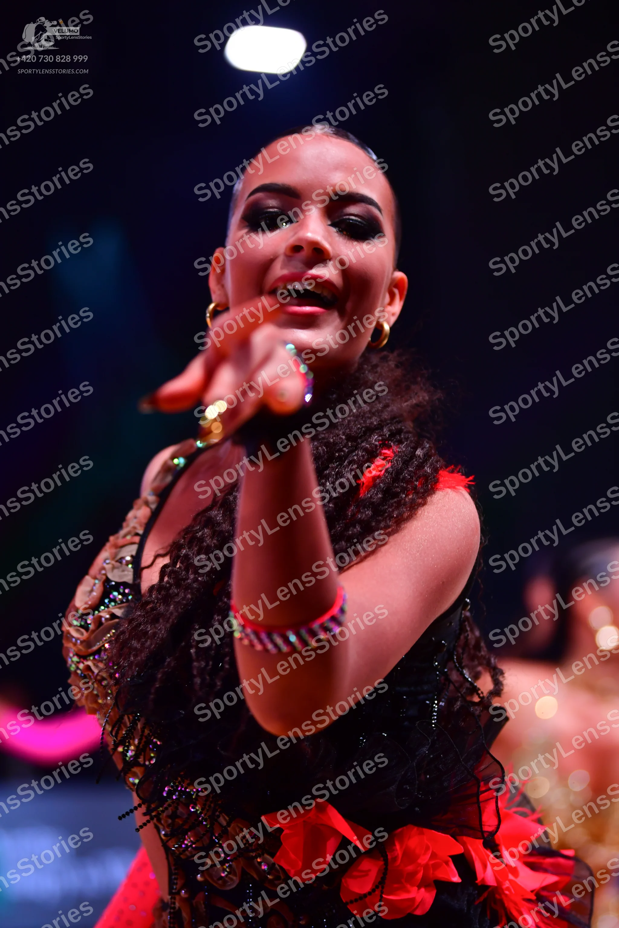 Dancesport competitor: Female dancer: black and red Latin dance dress heavily embellished with gold/bro