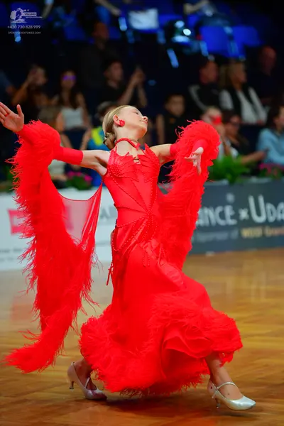 Dancesport competitor: Female dancer: red Latin dress with voluminous, textured, shredded-looking red f