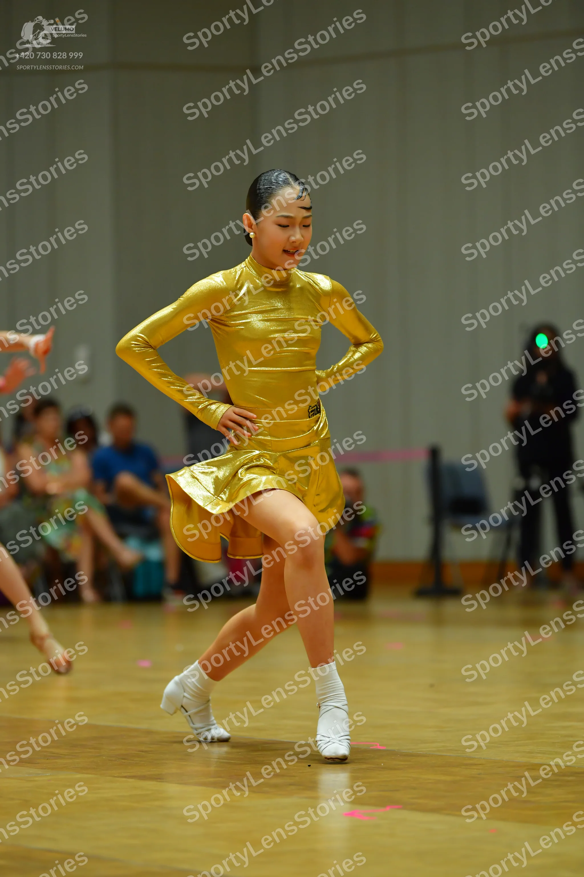 Dancesport competitor: Female dancer: gold metallic long-sleeved latin dress with a high neck and short