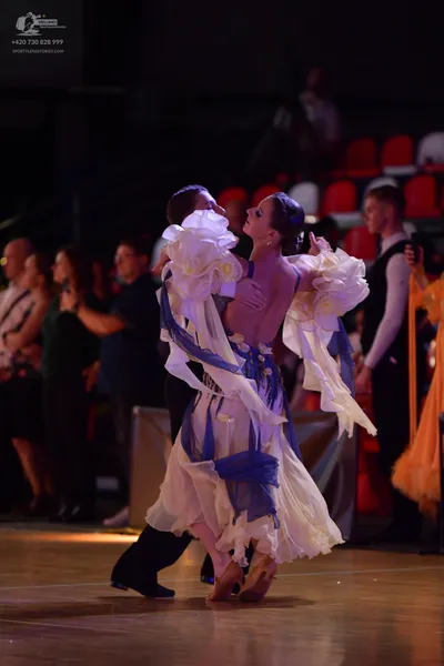 Dancesport competitor: Female dancer: white and cream-colored Latin-style dress with large, voluminous 